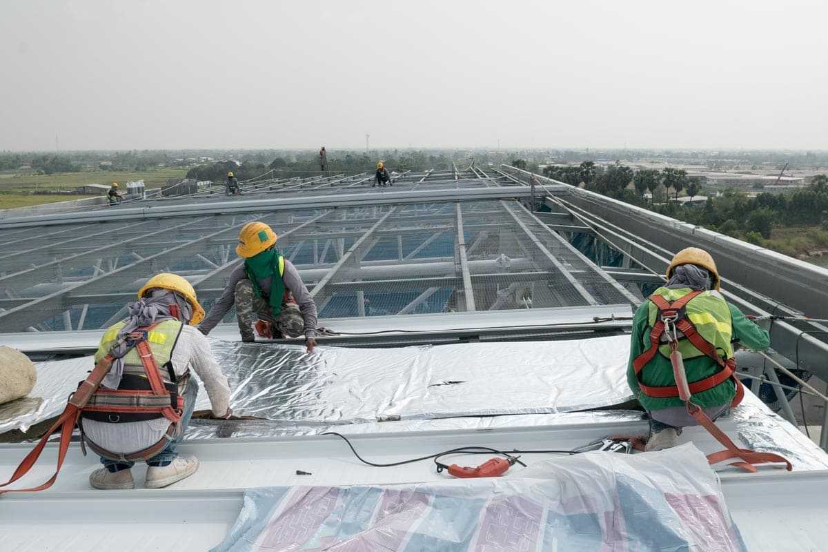 Construction-worker-wearing-safety-harness-and-safety-line-working-on-a-metal-industry-roof-new-warehouse (2)